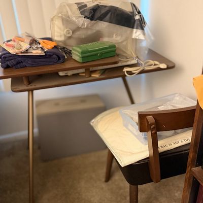 Mid-century style wooden sewing table equipped with a covered sewing machine, crafting notions, green accessory box, and matching chair.
