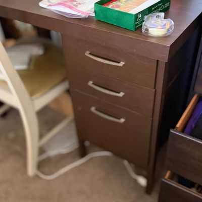 Dark brown wooden desk with a three-drawer cabinet base and curved silver-tone handles.