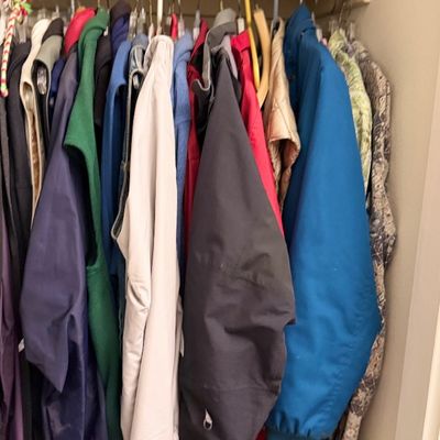 Collection of assorted winter jackets, coats, and vests hanging inside a closet.
