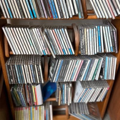 Large collection of music compact discs organized on a wooden shelf.