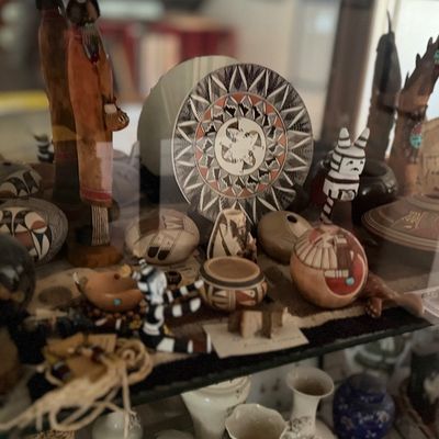 Collection of Native American artwork and pottery displayed in a glass cabinet.
