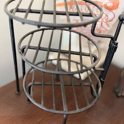 Sale Photo Thumbnail #112: Three-tiered black metal countertop rack with circular slatted shelves.