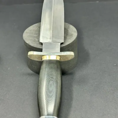 Sale Photo Thumbnail #149: Double-edged boot knife or dagger featuring a dark contoured wood-grain handle, brass and silver-toned fittings, and a polished stainless steel blade.
