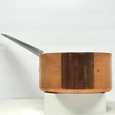 Sale Photo Thumbnail #98: Heavy gauge copper saucepan with a long cast metal handle, showing light surface tarnish and wear consistent with age.