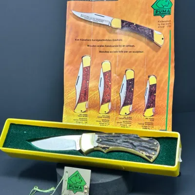 Sale Photo Thumbnail #189: Vintage Puma folding lockback knife with stag handle scales, shown with its original yellow presentation box, guarantee tag, and printed brochure.