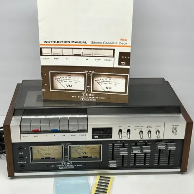 Sale Photo Thumbnail #52: Vintage TEAC 450 stereo cassette deck with original instruction manual, cleaning cloth, and accessories. Features analog VU meters, slider controls, and wood side panels from the 1970s.