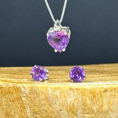 Sale Photo Thumbnail #168: Amethyst jewelry set including a heart-cut pendant necklace on a delicate silver-tone chain and matching round stud earrings.