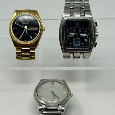 Sale Photo Thumbnail #121: Trio of men's wristwatches, including a gold-tone Seiko Quartz with a black dial, a Citizen Eco-Drive chronograph, and a silver-tone Seiko Quartz with a white dial.