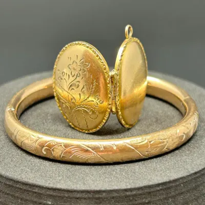 Sale Photo Thumbnail #184: Vintage gold-filled floral engraved hinged locket and matching engraved bangle bracelet, likely early to mid-20th century.
