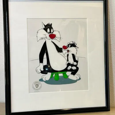 Sale Photo Thumbnail #100: Framed Looney Tunes animation cel featuring Sylvester the Cat and Sylvester Jr., stamped with a Warner Bros. seal of authenticity.