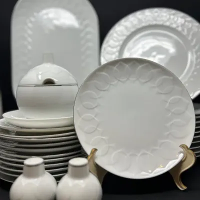 Sale Photo Thumbnail #101: Set of Rosenthal white porcelain dinnerware featuring raised leaf relief patterns and silver rims, including plates, a tureen, platters, and salt and pepper shakers.