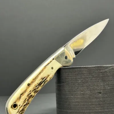 Sale Photo Thumbnail #183: Custom folding pocket knife featuring a polished steel blade etched '7 #15', nickel silver bolsters, and a textured stag horn handle with brass pin details.