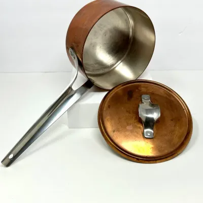 Sale Photo Thumbnail #143: Vintage heavy-gauge copper saucepan with stainless steel lining, long silver-tone handle, and matching lid.