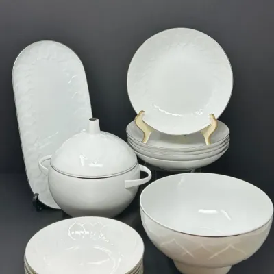 Sale Photo Thumbnail #11: White porcelain dinnerware set with platinum silver trim and subtle leaf or crosshatch texture, including a covered tureen, serving bowl, oval platter, plates, and shallow bowls.