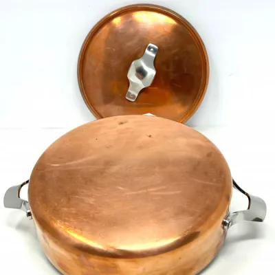 Sale Photo Thumbnail #103: Vintage copper Dutch oven pan with stainless steel handles and matching lid, showing minor surface wear from use.