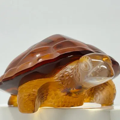 Sale Photo Thumbnail #115: Amber glass sea turtle figurine with textured shell and flippers, displayed on a light background.