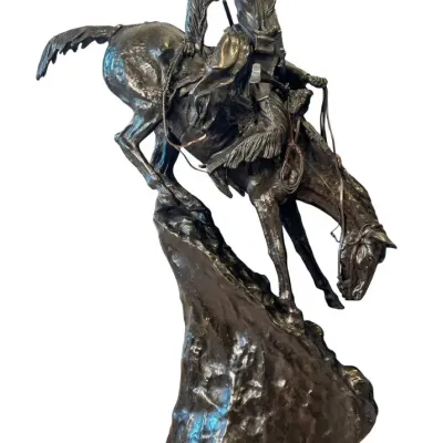 Sale Photo Thumbnail #59: Bronze sculpture after Frederic Remington's "The Mountain Man," depicting a trapper riding a horse down a steep rocky slope.