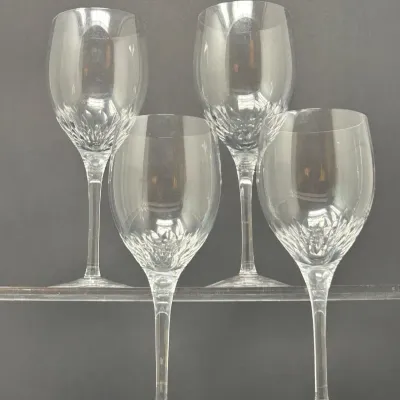 Sale Photo Thumbnail #78: Set of four clear crystal wine glasses featuring diamond-cut detailing near the base of the bowl and long, slender stems.