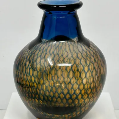 Sale Photo Thumbnail #105: Hand-blown art glass vase featuring a cobweb or scales motif over a golden interior with a cobalt blue neck and rim.