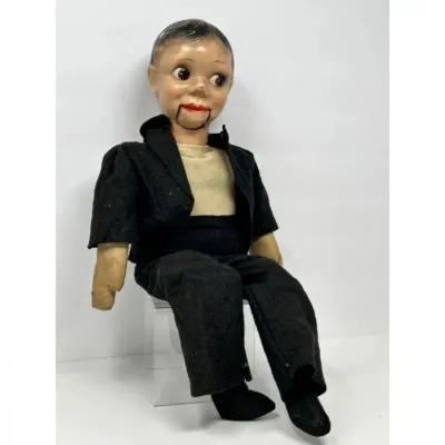 Sale Photo Thumbnail #212: Vintage composition Charlie McCarthy ventriloquist dummy wearing a black suit and tan shirt, showing minor age-related wear.