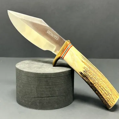 Sale Photo Thumbnail #167: Randall Made fixed-blade knife featuring a stag horn handle, brass handguard, and red, black, and white spacer rings. The stainless steel blade is stamped with the Randall Made Orlando, FLA maker's mark.