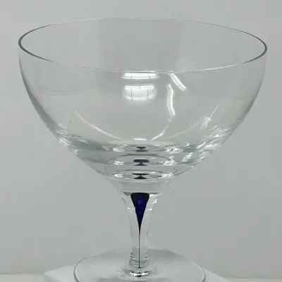 Sale Photo Thumbnail #94: Mid-century crystal coupe glass featuring a wide bowl and a clear stem with an encapsulated cobalt blue drop accent.