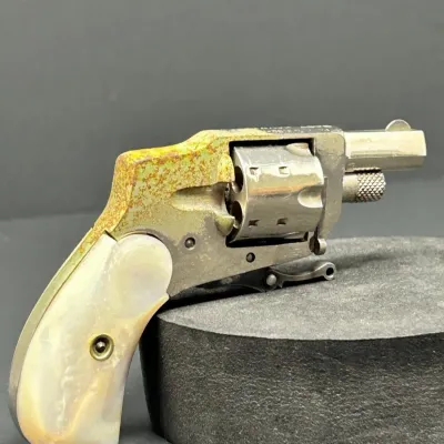 Sale Photo Thumbnail #9: Antique small-frame pocket revolver with mother-of-pearl grip scales, showing significant surface corrosion and wear on the metallic frame.