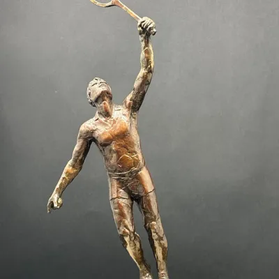 Sale Photo Thumbnail #70: Bronze sculpture of a male tennis player in mid-serve with a raised racket, mounted on a stone or marble plinth.