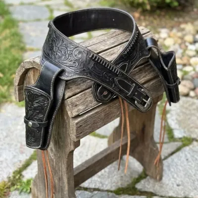 Sale Photo Thumbnail #10: Black floral-tooled leather double gun belt rig with matching holsters, cartridge loops, and silver-tone buckle.