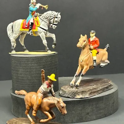 Sale Photo Thumbnail #172: Set of three vintage hand-painted lead or metal equestrian figurines, including a military bugler, a fox hunter in a red coat, and a cowboy on horseback.