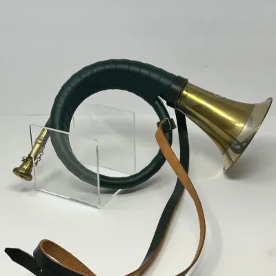 Sale Photo Thumbnail #127: Vintage brass fox hunting horn featuring a dark green leather-wrapped body, attached mouthpiece, and a long leather shoulder strap.