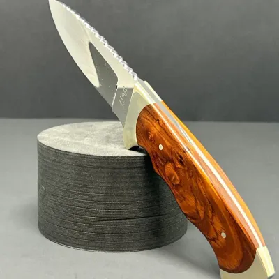 Sale Photo Thumbnail #122: Custom fixed-blade hunting knife with a polished steel blade, filework along the spine, stainless steel bolsters, and rich hardwood handle scales.