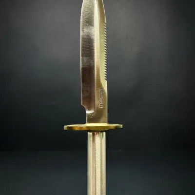 Sale Photo Thumbnail #210: Randall Made Model 18 Attack-Survival knife featuring a clip point blade with a sawback spine, brass double hilt, and hollow metal handle.