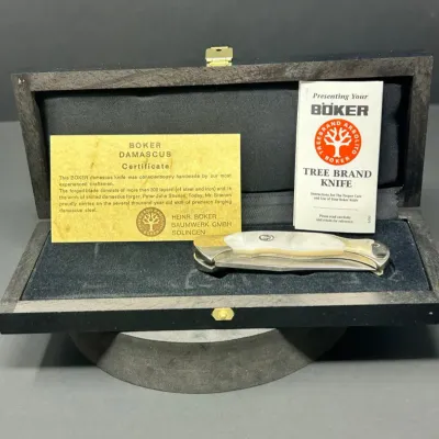 Sale Photo Thumbnail #173: Böker Tree Brand Damascus pocket knife with mother-of-pearl handle scales, complete with original wooden presentation case, certificate of authenticity, and care booklet.