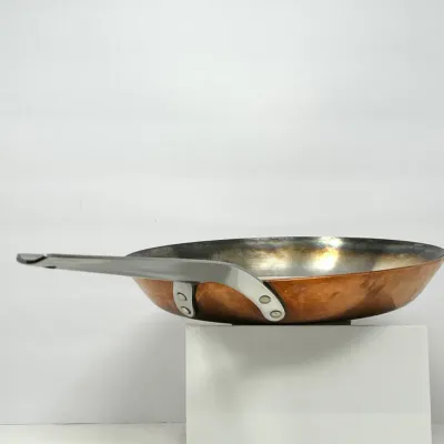 Sale Photo Thumbnail #29: Hammered copper skillet featuring a stainless steel handle attached with heavy-duty rivets and a metal-lined interior.
