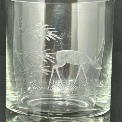 Sale Photo Thumbnail #37: Vintage clear glass tumbler featuring etched wheel-cut details of a deer grazing near pine trees.