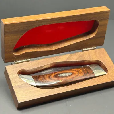 Sale Photo Thumbnail #193: Case XX folding pocket knife with a wood grain handle and nickel silver bolsters, housed in a custom hinged wooden display box with a red velvet insert.