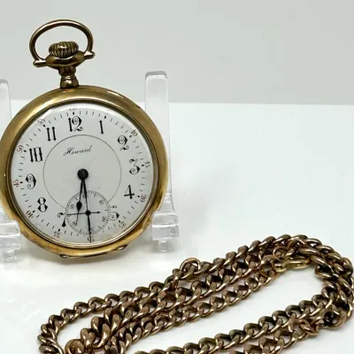Sale Photo Thumbnail #4: Vintage Howard open-face pocket watch in a gold-tone case, featuring a white dial with Arabic numerals, sub-seconds dial, and an accompanying curb link chain.