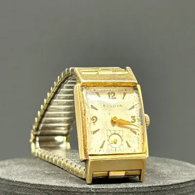 Sale Photo Thumbnail #186: Vintage Bulova rectangular men's wristwatch with gold-filled case and flexible expansion band, circa 1940s to 1950s. Features a sub-seconds dial and shows age-consistent wear and patina to the face and metal.