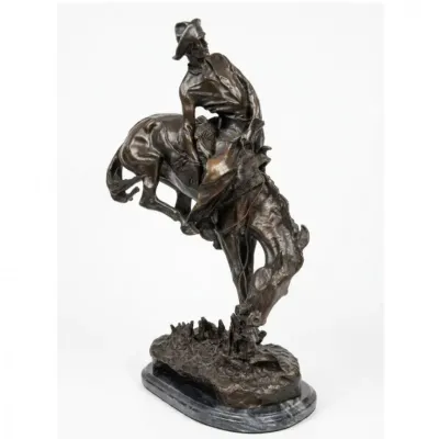 Sale Photo Thumbnail #214: Bronze sculpture after Frederic Remington titled "The Bronco Buster", featuring a cowboy riding a rearing horse set on a marble base.
