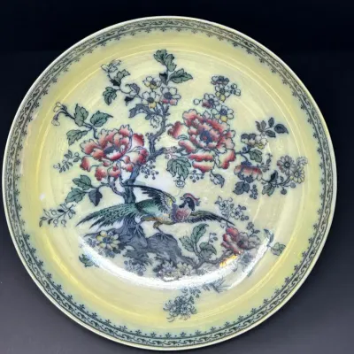 Sale Photo Thumbnail #161: Vintage Asian export porcelain display plate featuring a yellow background with a central design of a pheasant perched among floral branches and a patterned rim.