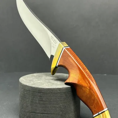 Sale Photo Thumbnail #56: Custom Davis Knives fixed-blade hunting knife featuring a polished trailing point blade, brass finger guard and pommel, and a contoured wood handle.