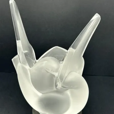 Sale Photo Thumbnail #45: Lalique-style frosted and clear crystal sculpture featuring two stylized birds with outstretched wings, displayed on a dark base.