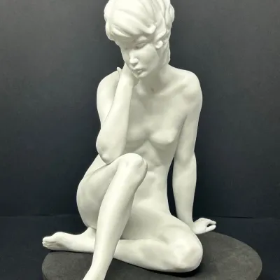 Sale Photo Thumbnail #66: Mid-century matte white bisque porcelain figurine depicting a seated female nude in a contemplative pose.