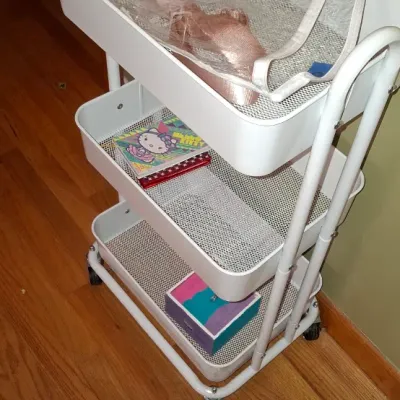 Sale Photo Thumbnail #68: White three-tiered metal rolling utility cart containing clear storage bags, a Hello Kitty notebook, and a small decorative box.