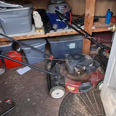 Sale Photo Thumbnail #134: Red Toro gas-powered push lawn mower stored in a shed alongside plastic storage totes and workshop supplies.