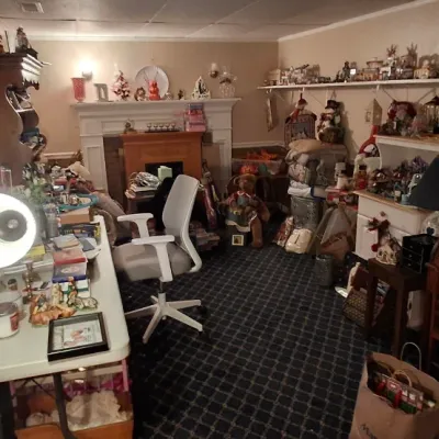 Sale Photo Thumbnail #110: Home office and craft room filled with furniture, collectibles, decorative items, shelves with model buildings, and a small roll-top desk.