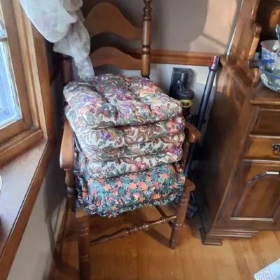 Sale Photo Thumbnail #33: Traditional wooden ladder-back dining chair stacked with four floral fabric seat cushions.