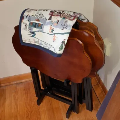 Sale Photo Thumbnail #31: Set of wooden folding TV tray tables stored on a matching stand, featuring a tapestry runner draped over the top.