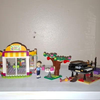 Sale Photo Thumbnail #124: Collection of assembled LEGO Friends playsets, including a grocery market, outdoor tree scene, piano, cart, and multi-story building.